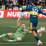 Intense soccer match moment with goalkeeper attempting save during game.