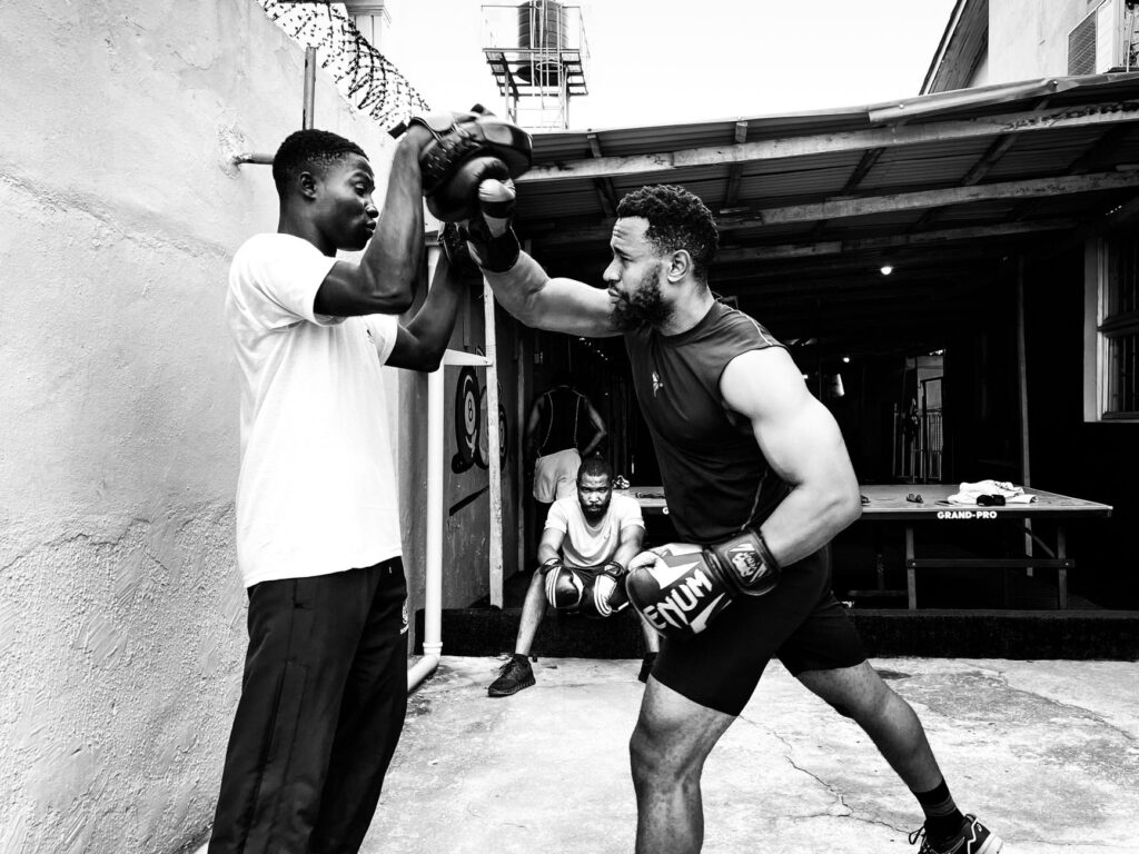Two men engaged in an outdoor boxing training, showcasing focus and strength.