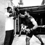 Two men engaged in an outdoor boxing training, showcasing focus and strength.