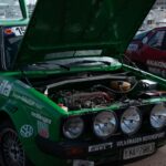 Green rally car with open hood, exposed engine at Monaco event.