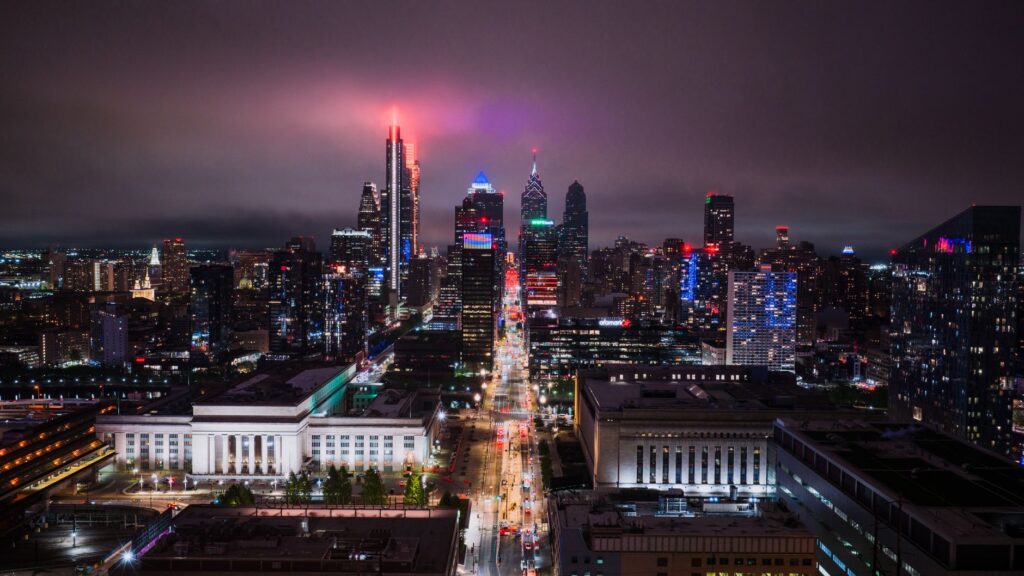 Stunning aerial view of Philadelphia's illuminated skyline at night, showcasing vibrant city lights.