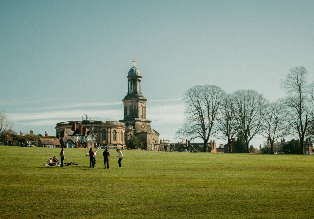 A sunny view of St Chad's Church and people relaxing in The Quarry, Shrewsbury.