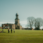 A sunny view of St Chad's Church and people relaxing in The Quarry, Shrewsbury.