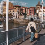 Vibrant street scene in Gijón, Spain featuring colorful architecture and a calm harbor.