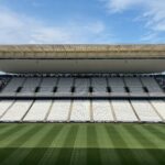 Wide view of an empty football arena in São Paulo, featuring a green pitch under a sunny sky.