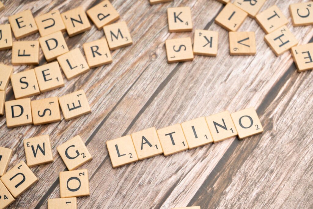 Wooden Scrabble tiles spelling 'Latino' on a textured wooden surface, emphasizing cultural identity.