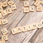 Wooden Scrabble tiles spelling 'Latino' on a textured wooden surface, emphasizing cultural identity.