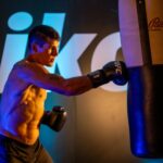 A male boxer trains intensely with a punching bag indoors at a gym in Mexico City.