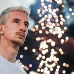 Portrait of a man with blonde hair gazing at festive lights in Moscow, Russia.
