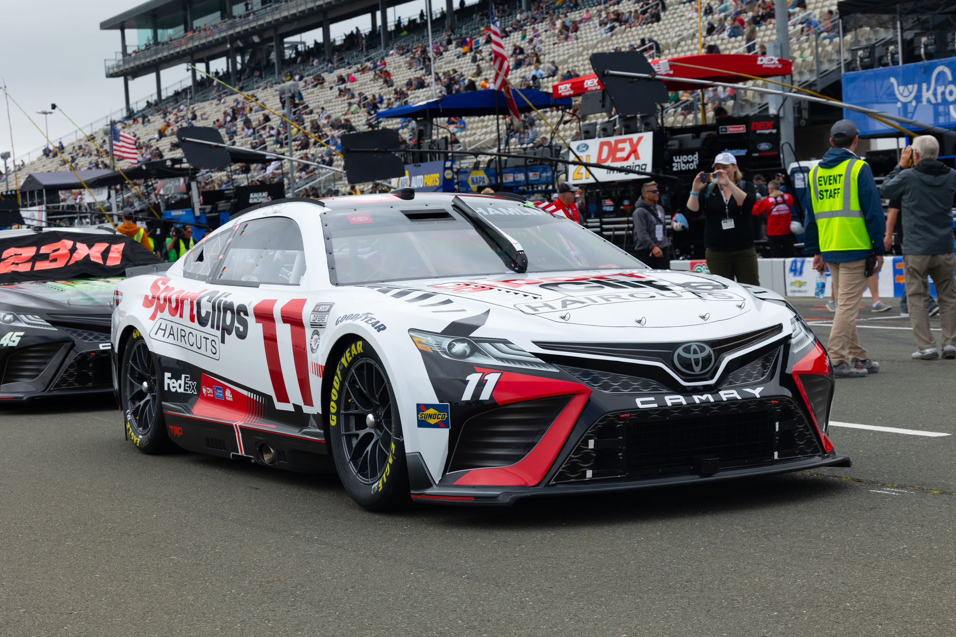 Toyota Camry race car with Sport Clips livery at a crowded racetrack, ready for action.