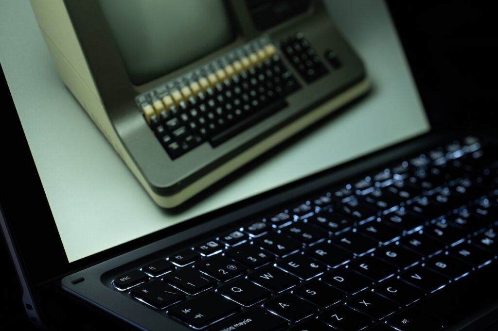 A vintage computer is reflected on a modern laptop screen, showcasing technological evolution.