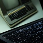 A vintage computer is reflected on a modern laptop screen, showcasing technological evolution.