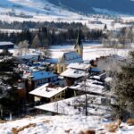Scenic winter view of Walchsee village with snow-covered houses and church in Tirol, Austria.