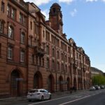 View of a historic red brick building on a street in Manchester on a clear day.