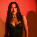 A striking portrait of a woman with bold red lighting and wet hair effect.