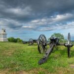 Historic cannons and memorial at Gettysburg, Pennsylvania, set against a dramatic sky.