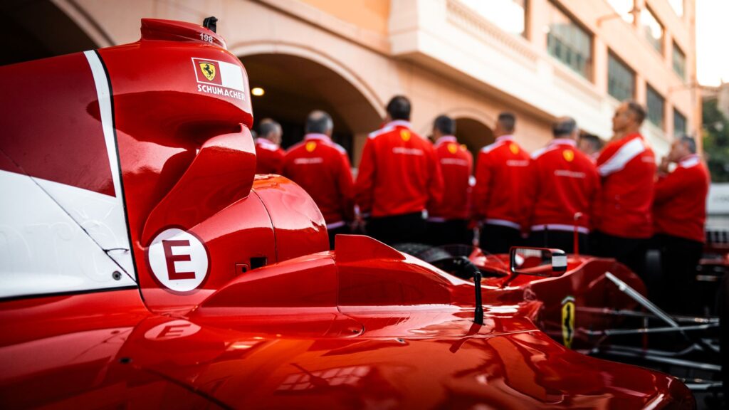 Close-up of a red Formula 1 car with team members in matching uniforms.