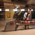 A man selects a bowling ball in a stylish and contemporary bowling center.