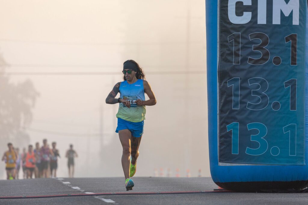 Focused runner at California International Marathon with distance marker in soft light.