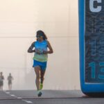Focused runner at California International Marathon with distance marker in soft light.