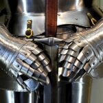 Detailed view of medieval armor gauntlets holding a sword.