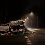 A wrecked car after a crash on a dimly lit street in Berlin at night.