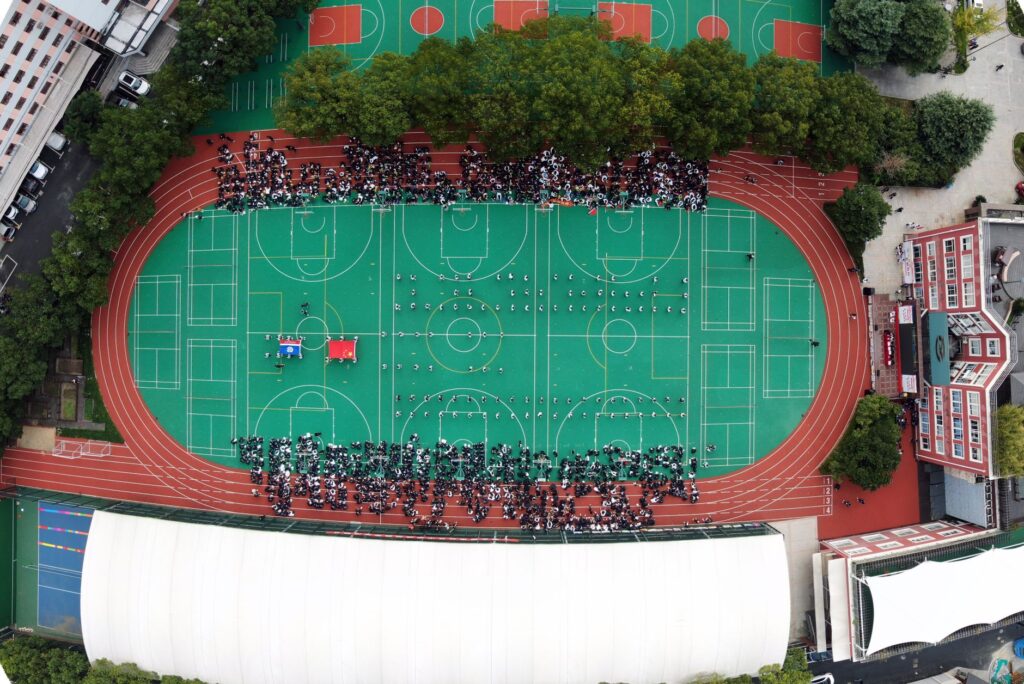 Aerial view of a sports complex in Shanghai with people gathered on a green field.
