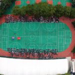 Aerial view of a sports complex in Shanghai with people gathered on a green field.