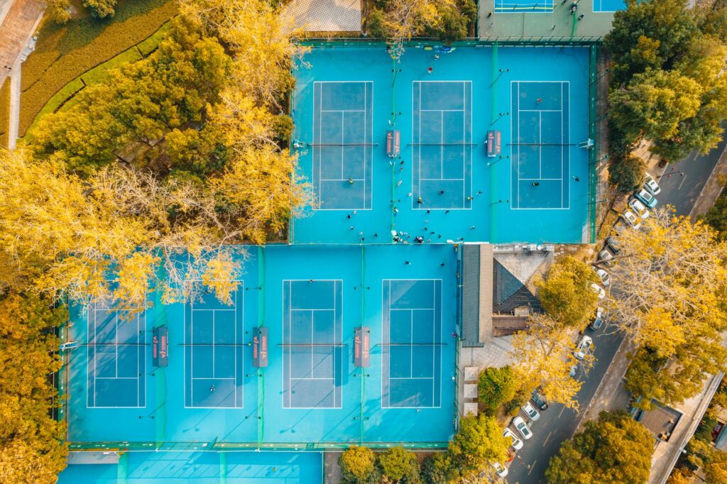 A vibrant aerial view showcasing multiple tennis courts surrounded by autumn trees.