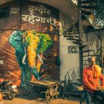 Vibrant street art featuring an elephant mural in Indore, India, with local men and a spiral staircase.