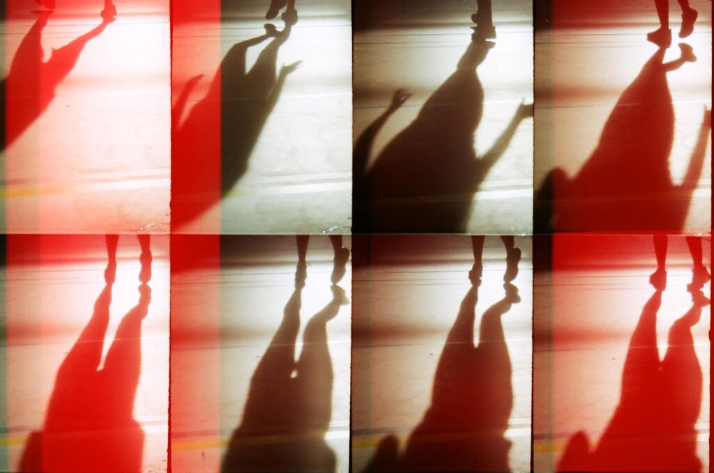 Creative and abstract silhouette shadows with red light overlay, featuring human forms.