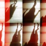 Creative and abstract silhouette shadows with red light overlay, featuring human forms.