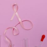 Pink ribbon symbolizing breast cancer awareness with laboratory glassware on a pink backdrop.