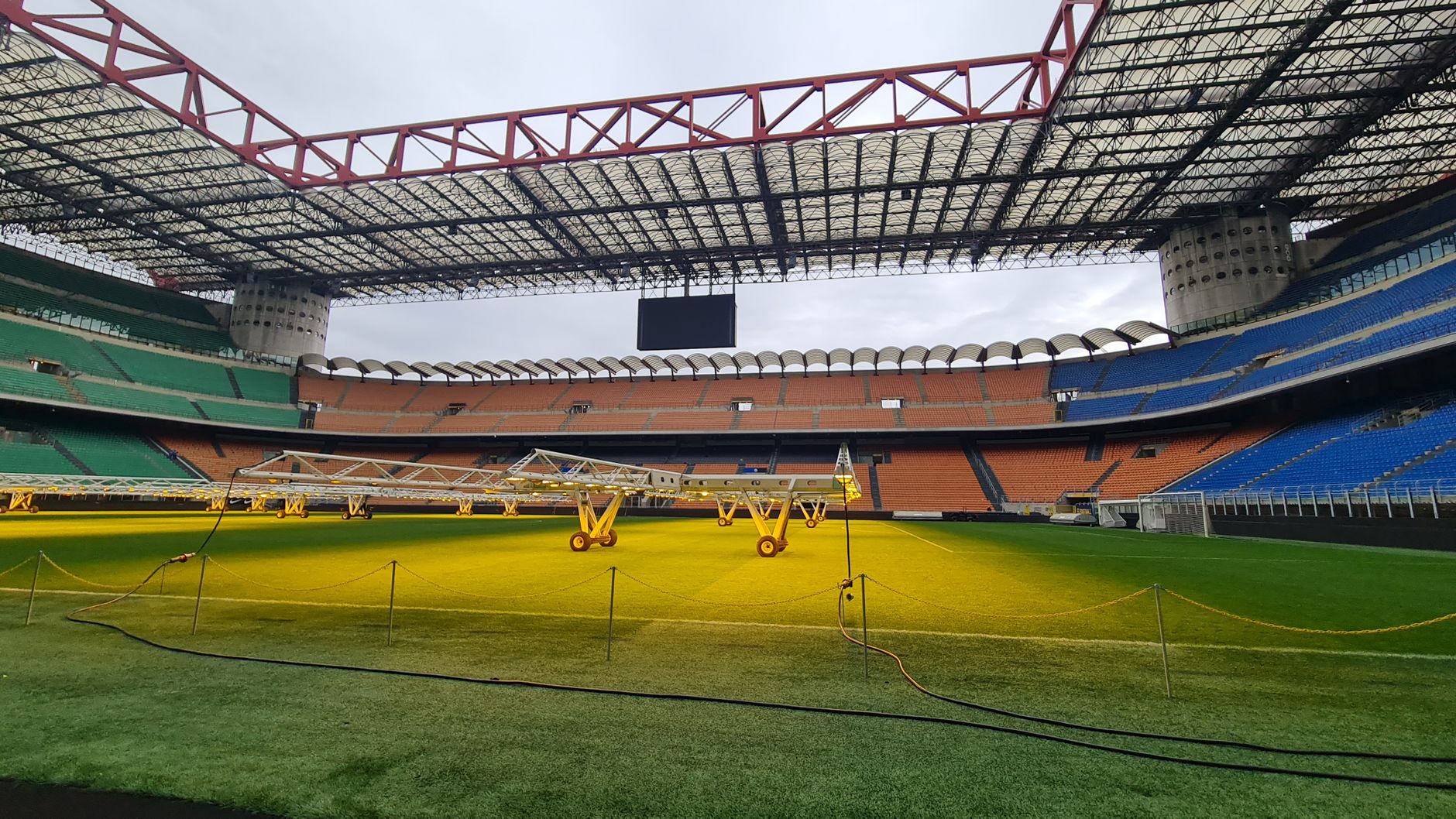 Wide-angle view of San Siro Stadium field, showcasing seating and lighting equipment inside the iconic venue.