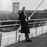 Elegant black and white portrait of a man on a modern bridge in Manchester, UK.