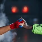 Close-up of two wrapped hands in a fist bump amid smoke, symbolizing unity in martial arts.