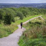 A cyclist rides down a winding path in the lush greenery of Silverdale, England.