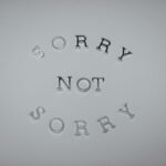 Minimalist design featuring the phrase 'Sorry Not Sorry' arranged in a circular pattern on a white background.