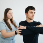 A physiotherapist assists a patient with arm exercises in a clinical setting.