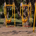 Two bright yellow and red swings in a quiet park in İzmir, Türkiye.