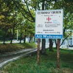 Welcome sign outside St. Thomas' Church surrounded by lush greenery and trees.