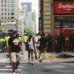 A vibrant street corner in New York City with pedestrians and police officers in the summer.