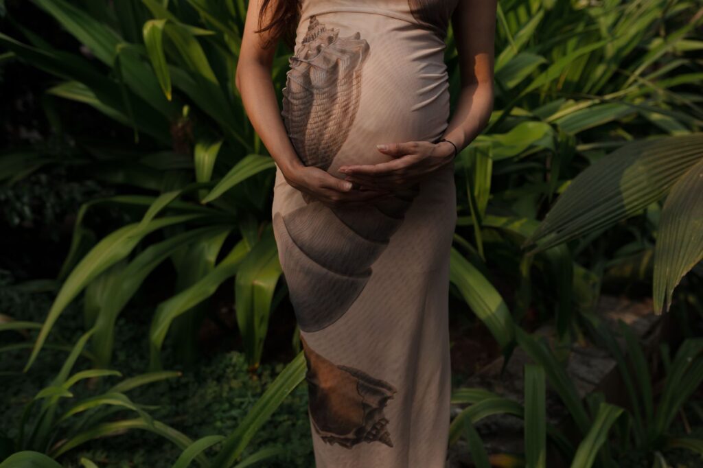 Expectant mother embracing nature in a lush green garden.