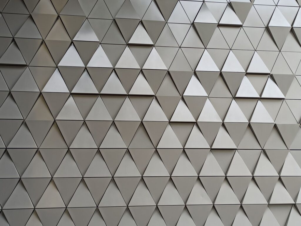 Close-up of modern architectural wall with 3D triangular panels in a metallic finish.