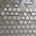 Close-up of modern architectural wall with 3D triangular panels in a metallic finish.