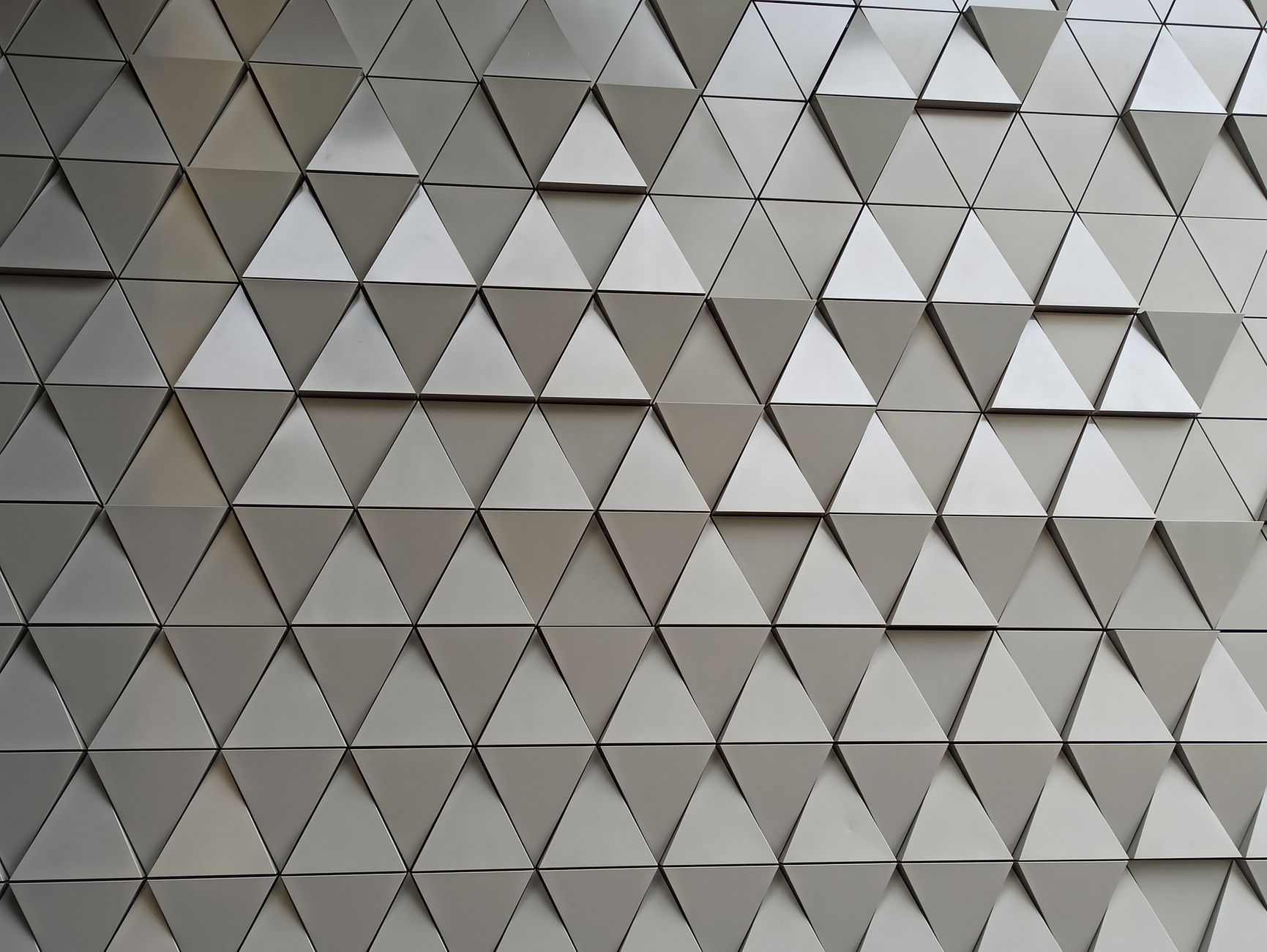 Close-up of modern architectural wall with 3D triangular panels in a metallic finish.