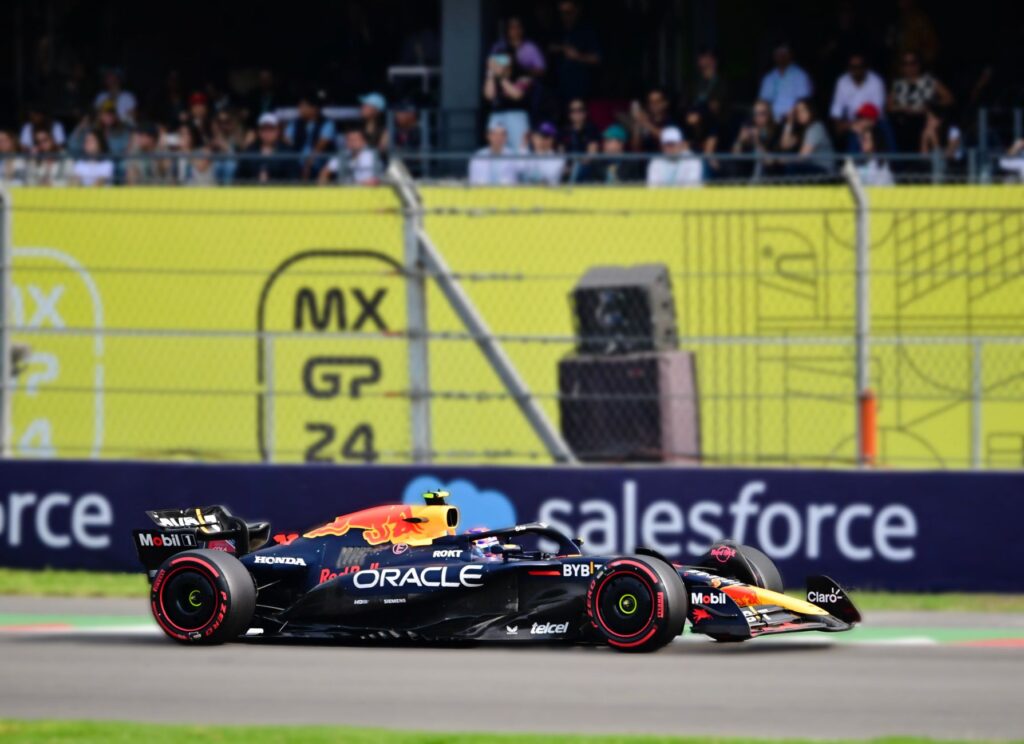 Dynamic shot of an F1 car racing at Mexico City Grand Prix with a cheering crowd in the background.