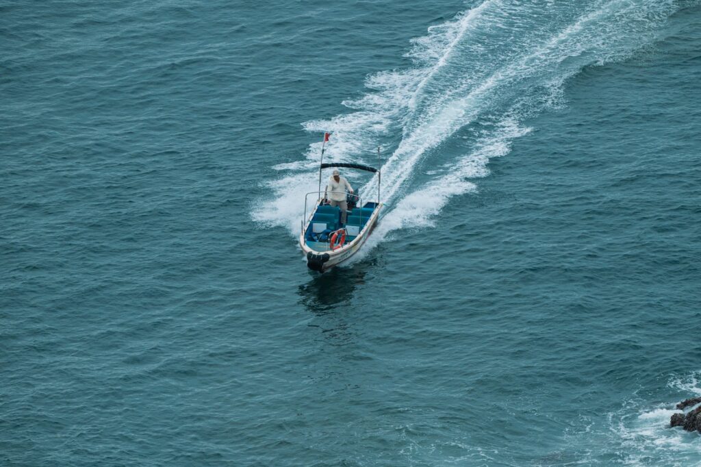 Aerial view of a motorboat speeding through the ocean, creating a dynamic water trail.