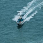 Aerial view of a motorboat speeding through the ocean, creating a dynamic water trail.