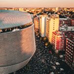 Aerial view of a stadium and bustling cityscape in Madrid, Spain during sunset.